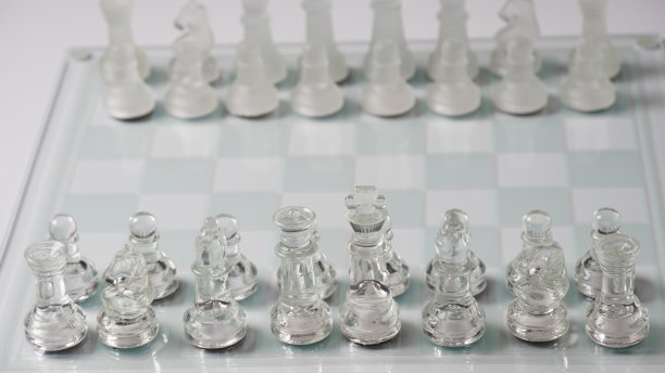 反射棋盘上起始位置的透明国际象棋棋子图片下载