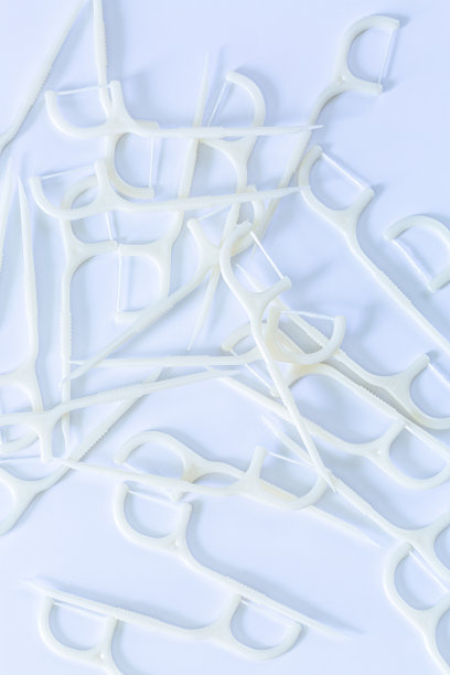 白色背景上的清洁牙线。牙科保健的概念。白色牙签与牙线隔离白色塑料牙签与牙线图片下载