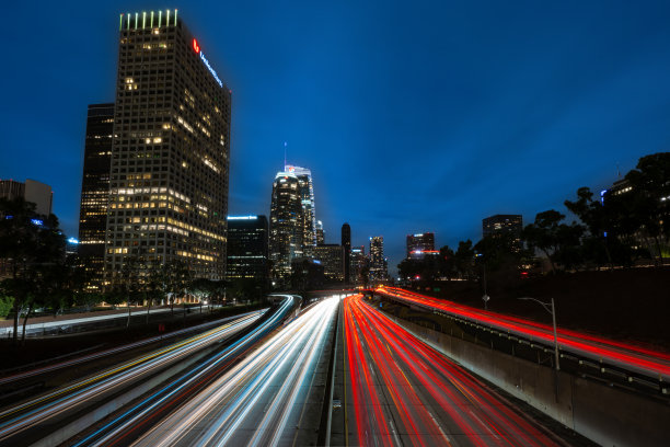 夜晚的洛杉矶市中心高速公路，蓝天和长时间曝光的车灯轨迹。图片下载