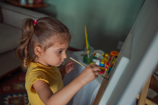 小女孩在画布架上画画图片下载