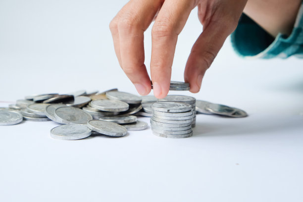 人类的手在白色背景上堆叠硬币，工作室拍摄图片下载