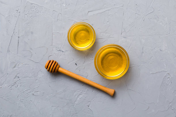 玻璃罐蜂蜜与木制雨淋在彩色背景。蜂蜜罐和勺子高高在上。俯视图复制空间图片下载