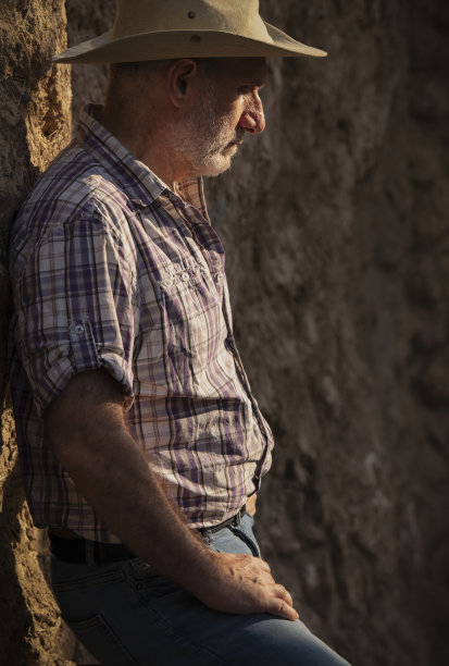 侧面的成年人在牛仔帽和衬衫对着废弃的建筑图片下载