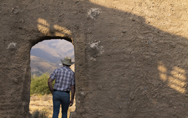 成年男子在牛仔帽和衬衫背面站在门口的背景建筑图片下载