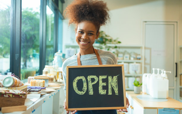 穿着围裙的年轻女老板在零废物商店卖超级食品。小生意:咖啡馆的老板很开心，她的招牌在营业。图片下载