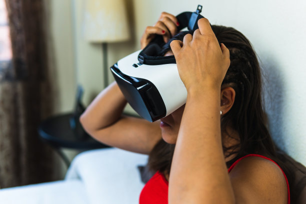 黑发扎着辫子的女人试图戴上虚拟现实眼镜开始体验。小女孩在她的房间里通过她的数字设备启动增强现实可视化。图片下载