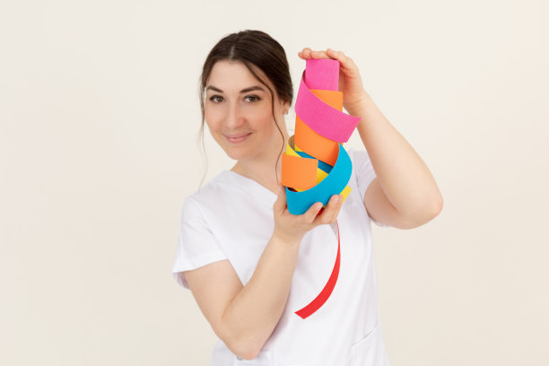 女医疗治疗师，医生看着镜头，展示，广告彩色肌内修磁带手动应用。广告图片下载