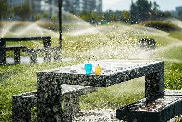 透明塑料杯是黄色和蓝色的饮料是在室外焦点的前景垂直照片水滴在花园的桌子上图片下载