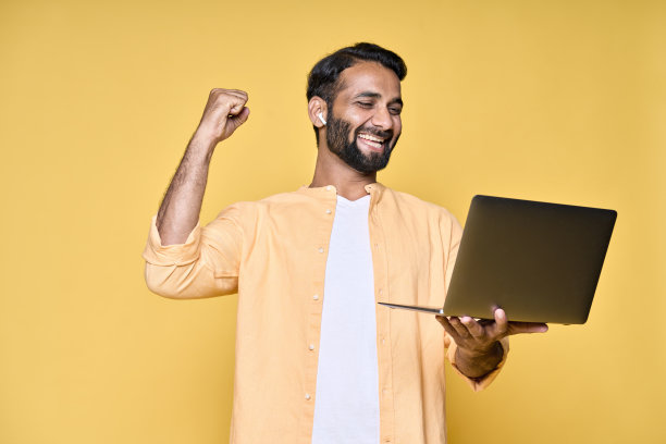 快乐的印度男子举起拳头，在笔记本电脑上看比赛图片下载
