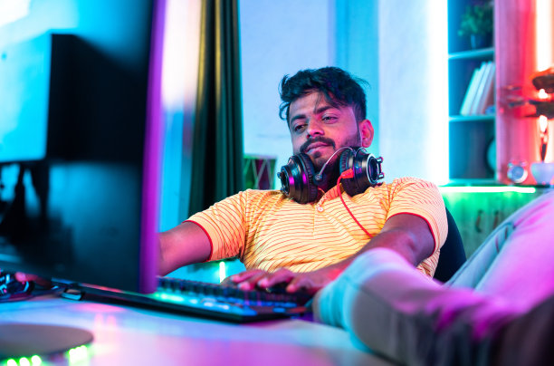 一名年轻人在假期在家玩电脑游戏，这是疲惫、懒惰和娱乐的概念图片下载