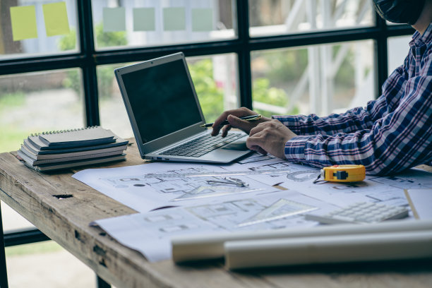 在一间现代化的办公室里，一位建筑师的手绘打印工程师在一张桌子上讨论建筑蓝图和楼层平面图。图片下载