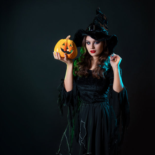 一个年轻漂亮的女巫戴着圆锥形的帽子，手里拿着一个万圣节南瓜图片下载