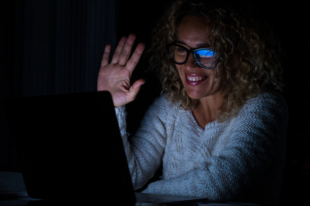 前视图女员工在在线活动简报中与不同同事进行视频通话。女性员工晚上在家里用现代化的笔记本电脑与同事进行小组会议。图片下载