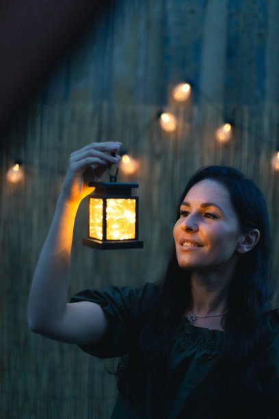 一个迷人的女人拿着复古的手电筒在黄昏。图片下载