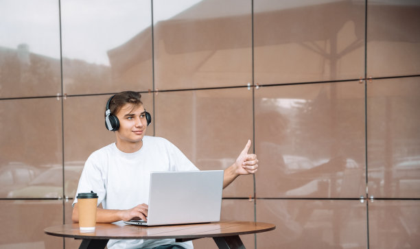 男生戴着耳机，在户外用笔记本电脑。有选择性的重点图片下载