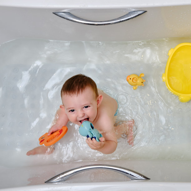 快乐的蹒跚学步的小男孩正在浴缸里玩玩具。一个微笑的孩子在家庭浴室的水里玩耍图片下载