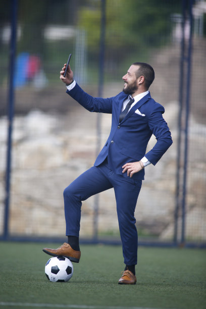 商人用他的手机和足球场里的一个球自拍图片下载