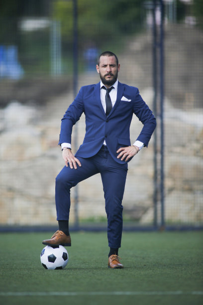 一个商人在足球场里用脚踩着球摆姿势图片下载