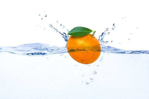 橙色的果实和绿色的叶子掉落在水花中图片下载