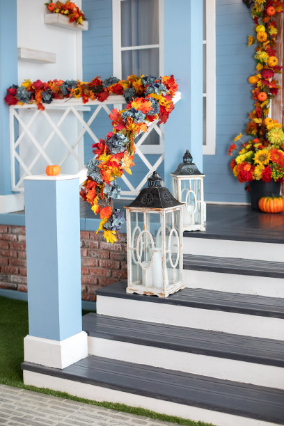 舒适的门廊的房子与木灯笼在秋天的时间。万圣节用黄色的落叶和灯设计的家。房屋入口楼梯装饰为秋天的节日，秋天的花朵和南瓜。图片下载