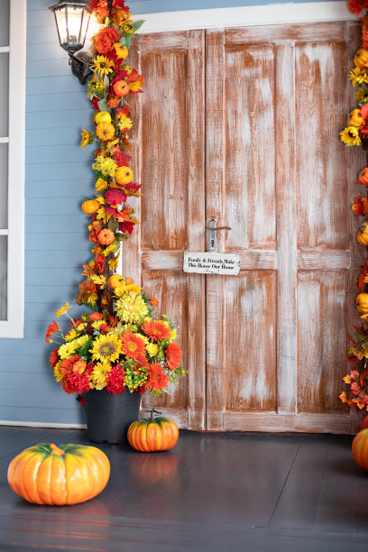 万圣节的构图设计家与黄色的落叶和花朵。房屋入口楼梯装饰为秋天的节日，秋天的花朵和南瓜。舒适的木制门廊的房子与南瓜在秋天图片下载