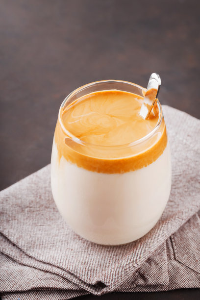 自制的达尔戈纳咖啡，深色背景。达尔戈纳(Dalgona)泡沫咖啡，用勺子放在亚麻餐巾上。韩式速溶咖啡，加糖和牛奶图片下载