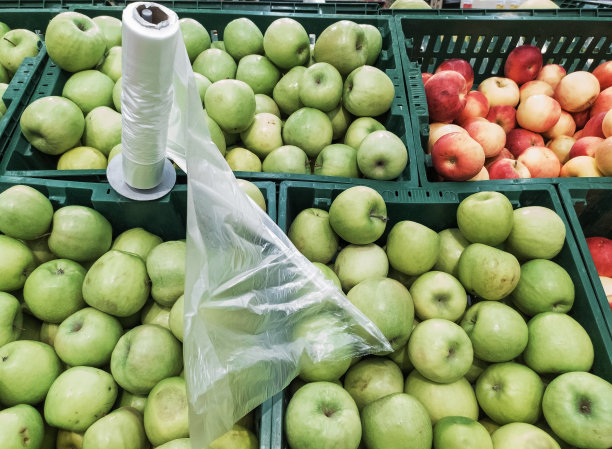 我在超市买青苹果。农贸市场田地里多汁的苹果。苹果旁边是一卷包装袋。图片下载