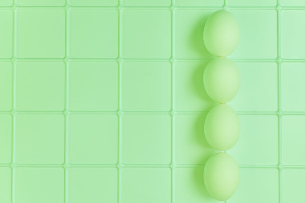 四个鸡蛋放在绿色格子塑料表面上。图片下载