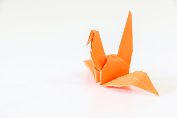 白色背景右侧的橙色日本折纸鹤图片下载