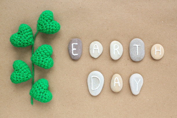 地球日的字母从鹅卵石和钩针叶在工艺纸背景。图片下载