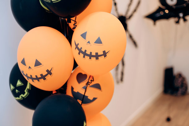 橘红色和黑色的气球，上面有吓人的万圣节鬼脸。万圣节装饰图片下载