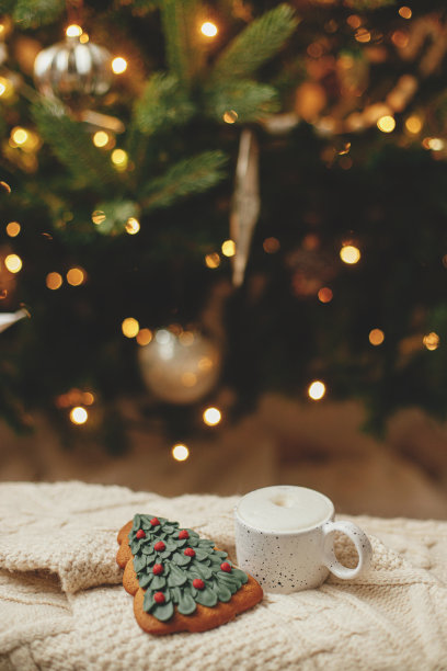 大气冬季hygge。温暖的咖啡和圣诞树姜饼饼干在针织毛衣背景的圣诞树与灯。圣诞节的旗帜。舒适的假期图片下载