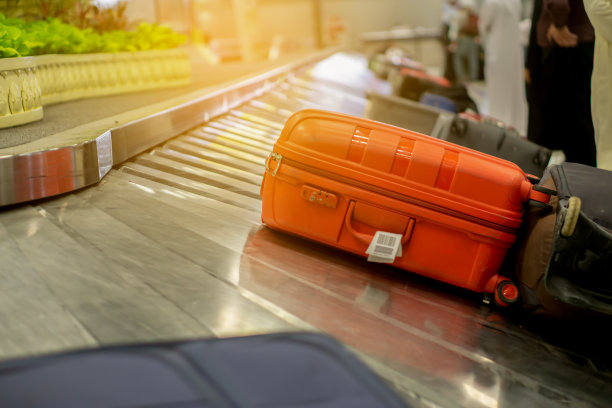 乘飞机旅行后，旅客在扫描仪处等候行李。以机场柜台传送带上的行李x光机带为背景，商务旅行概念图片下载