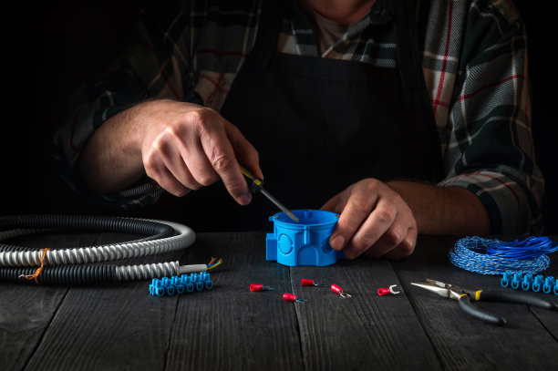 电工大师工作时的手特写。正在安装连接到蓝色接线盒的电缆或电线。对电气设备的安装和维修有想法。图片下载