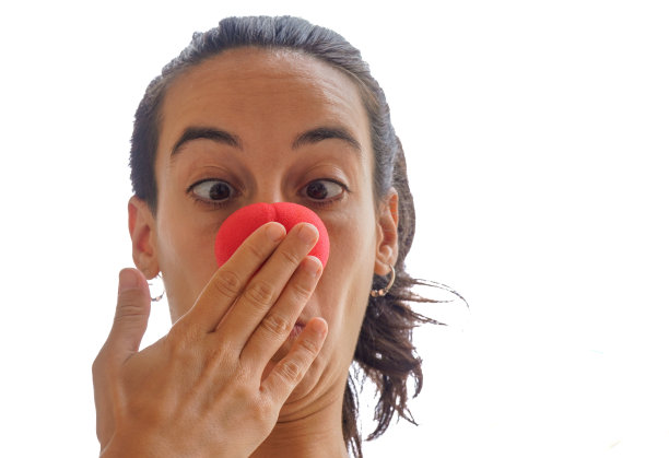 小丑惊讶。长着小丑红鼻子的女孩惊讶地从她手中挣脱出来。图片下载