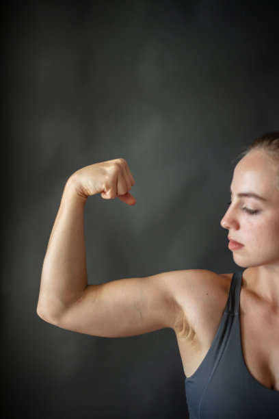 美丽的金发女人展示她的手臂肌肉。图片下载