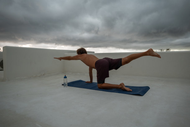 在屋顶上练习瑜伽和伸展身体的年轻人图片下载