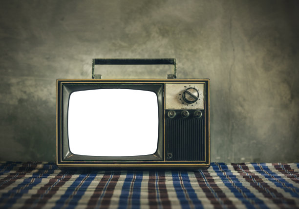 复古的老电视在布桌子上与切割屏幕在旧水泥墙的背景图片下载
