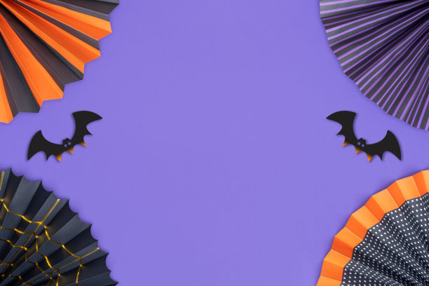 万圣节的背景。框架由明亮的纸扇和蝙蝠在紫色的背景与复制空间。图片下载