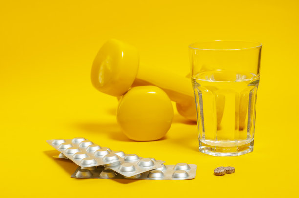 银色的盘子，旁边放着没有包装的药片和药片，背景是一杯饮用水和哑铃。图片下载