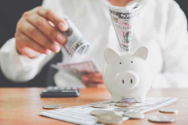 节能省钱的理念。储蓄或投资的想法。商人手把钞票钞票放进小猪存钱和理财概念，钱硬币概念理财。图片下载