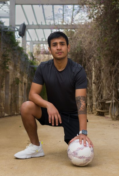 年轻的秘鲁人跪在走廊上，用左手触碰地上的一个球图片下载