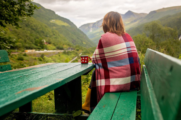 年轻女子在挪威享受峡湾，山脉和其他美丽的自然美景，在野外露营时吃早餐和咖啡图片下载