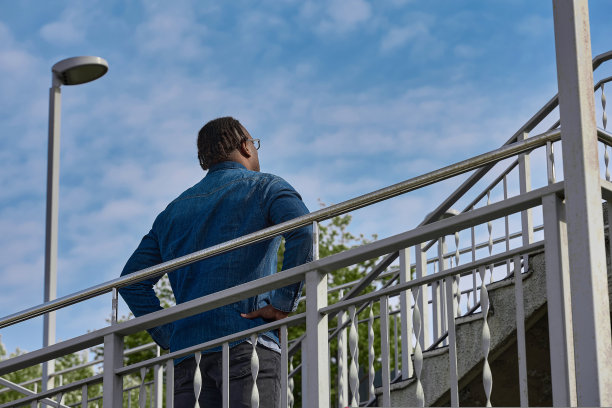 一个留着非洲发型的男人慢慢地短暂地爬上陡峭的楼梯图片下载