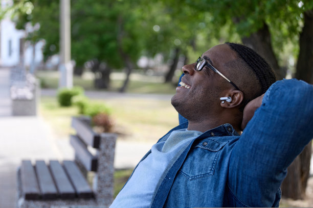 自由职业者们坐在城市巷子里的长凳上，享受着阳光明媚的日子，远离了严格的工作图片下载