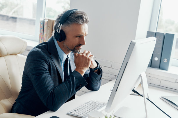 自信的商人戴着耳机坐在他的工作场所进行网络会议图片下载