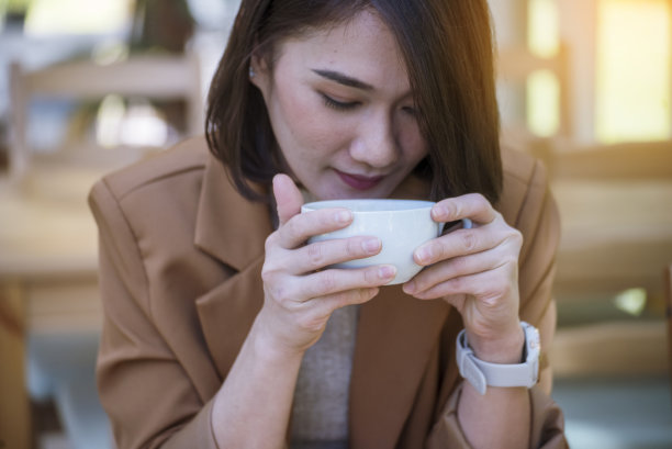 女商人的手喜欢喝热咖啡。在绿色花园咖啡馆，手持黑咖啡杯的女子。商务女性在咖啡店喝黑咖啡或热巧克力。咖啡因饮用图片下载