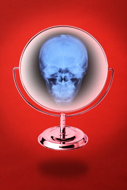 在红色背景的衬托下，漂浮在半空中的幽灵般的镜子里倒映着骷髅图片下载