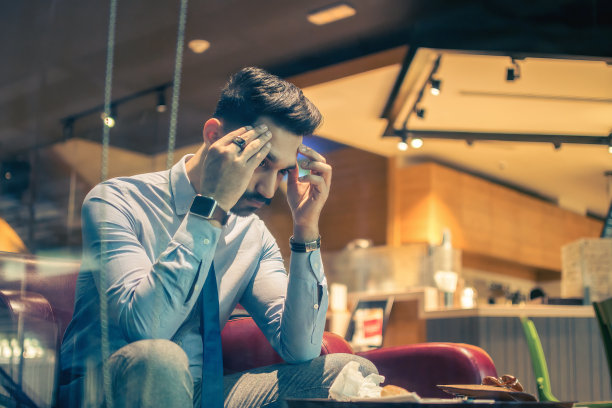 坐在咖啡店里，因严重头痛而痛苦的疲惫商人图片下载