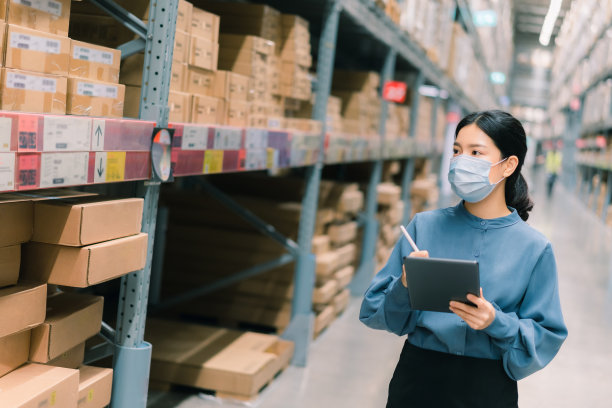 年轻聪明的亚洲商业工作妇女戴着外科口罩，使用数字平板电脑检查货架上的商品，在仓库的产品管理，物流业务规划概念与复制空间图片下载